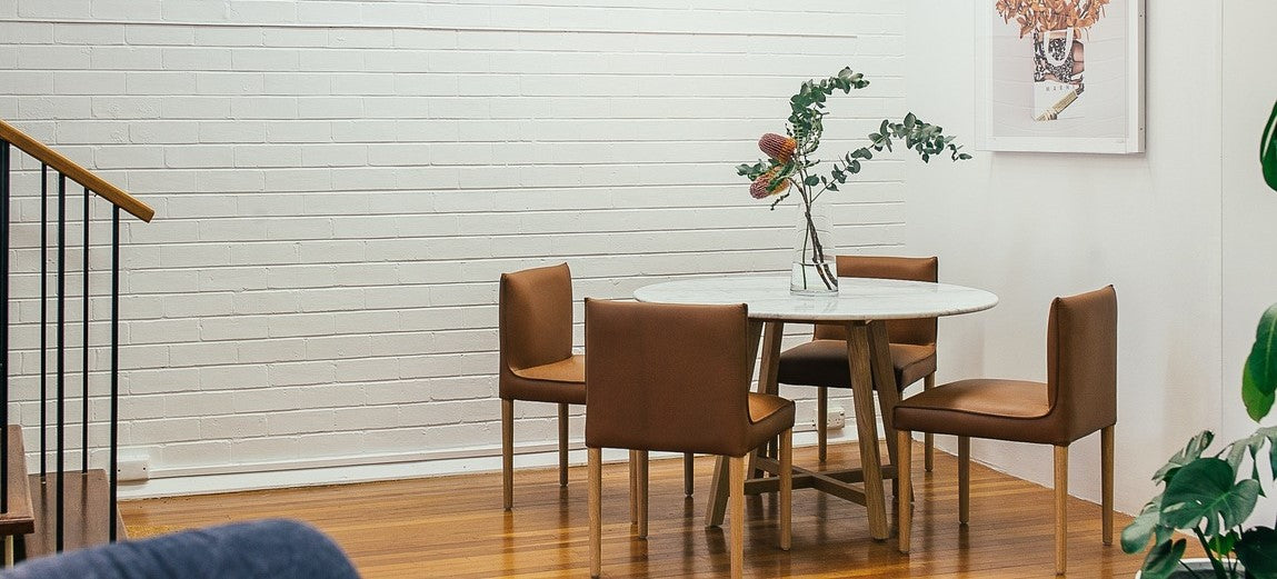 Bruine eetkamer stoelen aan een ronde witte tafel